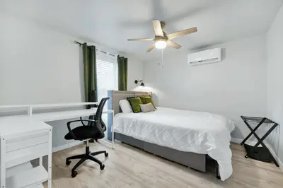 a bedroom with a bed and a desk and a ceiling fan at Cozy 2bd 2bth House Walk to Local Gems in Orlando