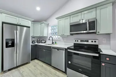 a kitchen with white cabinets and a stainless steel refrigerator at Cozy 2bd 2bth House Walk to Local Gems in Orlando