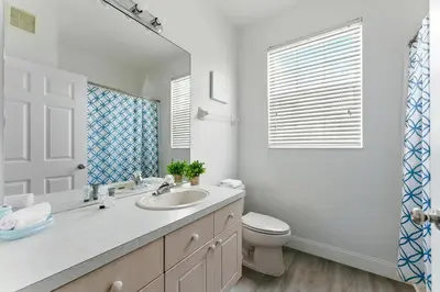 a bathroom with a sink and a toilet and a mirror at 3BR Resort Condo Pool Balcony Near Disney in Kissimmee