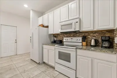 a kitchen with white cabinets and a white refrigerator at 4 Bedrooms 5 Bathrooms Bella Vida 871Mb in Kissimmee