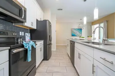 a kitchen with white cabinets and a black refrigerator at Refúgio 4Q com Piscina em Storey Lake in Kissimmee