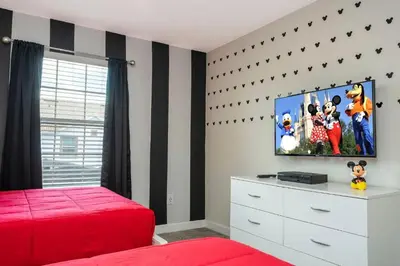 a bedroom with a red bed and a flat screen tv at Refúgio 4Q com Piscina em Storey Lake in Kissimmee