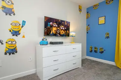 a bedroom with a tv on a wall with minions cartoons at Refúgio 4Q com Piscina em Storey Lake in Kissimmee