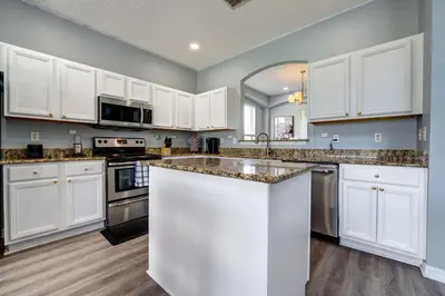 a kitchen with white cabinets and granite counter tops at Terra Verde Lakeview Escape in Kissimmee