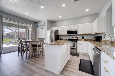 a kitchen with white cabinets and a table with chairs at Terra Verde Lakeview Escape in Kissimmee