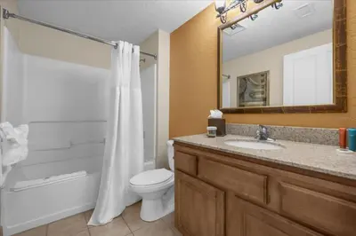 a bathroom with a toilet and a sink and a mirror at Resort Style Condo 4 miles from Disney in Orlando