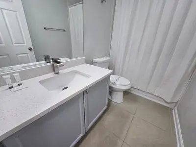 a white bathroom with a sink and a toilet at 4BRRenovateNO Resort feePrivate PoolDisney in Kissimmee