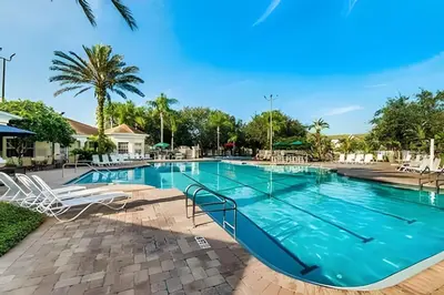 a swimming pool at a resort with chairs and trees at 4BRRenovateNO Resort feePrivate PoolDisney in Kissimmee