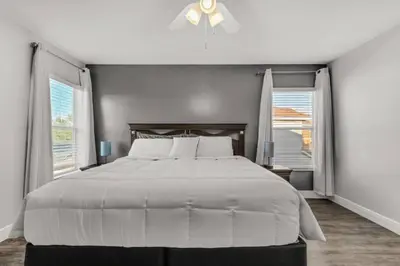 a bedroom with a large bed and two windows at 6 Bedrooms - 5,5 Bathrooms - Bella Vida 4529Ss in Kissimmee