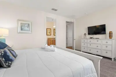 a white bedroom with a large white bed and a dresser at 361 Pendant ct in Orlando