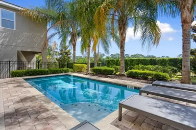 a swimming pool with a bench and palm trees at 361 Pendant ct in Orlando