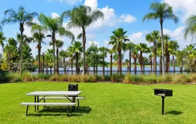 a picnic table and a grill in a park with palm trees at 3-Story sanctuary Condo in the heart of Orlando85 in Orlando