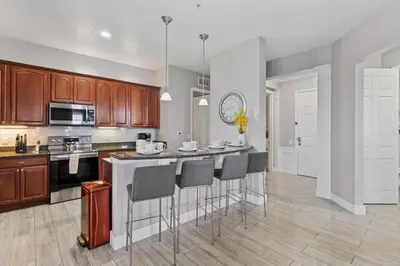 a kitchen with wooden cabinets and a island with bar stools at 5048 Light and Airy Resort 4BD Apartment 407 in Orlando