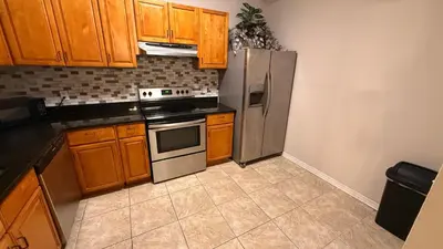 a kitchen with wooden cabinets and a stainless steel refrigerator at M13 Large Master Room with Private Bathroom & Smart TV in Orlando