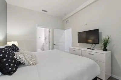 a white bedroom with a white bed and a television at Gorgeous Waterview ,Top Floor, 2Bd Condo, Storey Lake Resort in Kissimmee