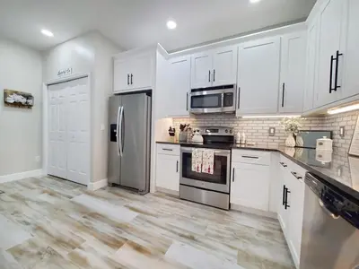 a kitchen with white cabinets and a stainless steel refrigerator at Gated 3BR 3BA Townhome Near Disney w Pool and Gym in Orlando