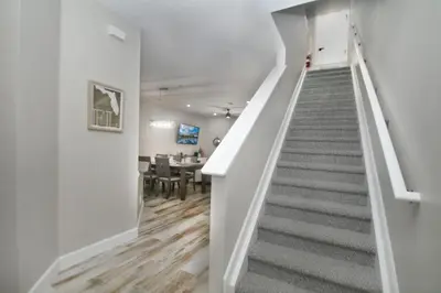 a hallway with a staircase and a dining room at Gated 3BR 3BA Townhome Near Disney w Pool and Gym in Orlando