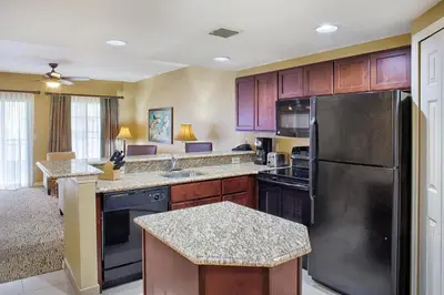 a kitchen with wooden cabinets and a stainless steel refrigerator at Wyndham Cypress Palms 1BR Apartment with Resort Access in Kissimmee
