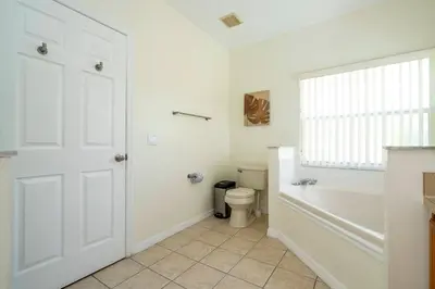 a bathroom with a toilet and a tub and a window at Amazing 6 bedrooms with pool in Kissimmee