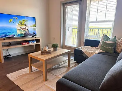 a living room with a couch and a flat screen tv at Modern Oasis with King Bed, Fireworks View, 10 Minutes to Disney in Orlando