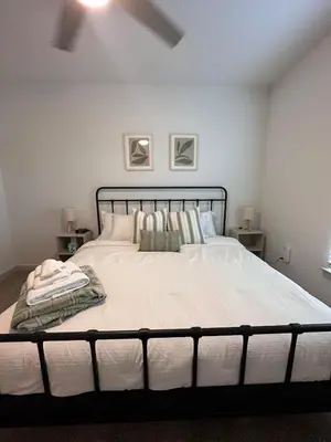 a bedroom with a bed with white sheets and pillows at Modern Oasis with King Bed, Fireworks View, 10 Minutes to Disney in Orlando
