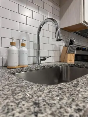 a kitchen sink with two bottles on a counter at Modern Oasis with King Bed, Fireworks View, 10 Minutes to Disney in Orlando