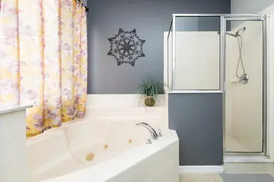 a bathroom with a tub and a refrigerator at Be Our Guest at Emerald Island in Kissimmee