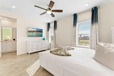 a bedroom with a white bed and a ceiling fan at Capri Sunset in Orlando