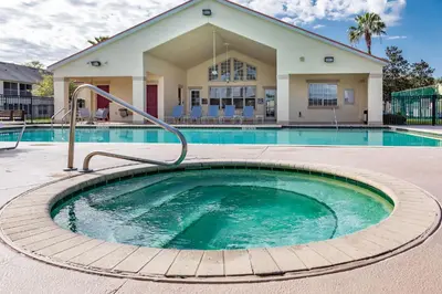 a swimming pool with a hot tub in front of a building at Celebrate at Club Cortile in Kissimmee