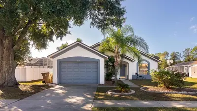 a house with a garage and a palm tree at Cozy on Cavendish - Themed bedrooms in Kissimmee