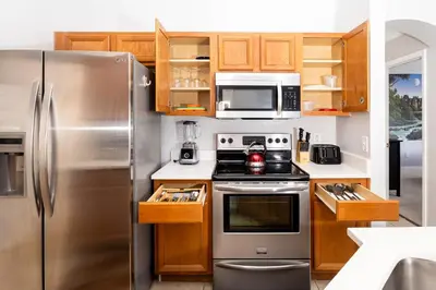 a kitchen with stainless steel appliances and wooden cabinets at Emerald Island Happy Place in Kissimmee