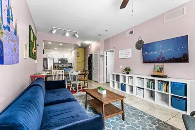 a living room with a blue couch and a tv at Enchanted At 7 Dwarfs Lane in Kissimmee