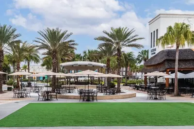 a courtyard with tables and chairs and palm trees at Wonderland at White Crane - Hot tub & Lake views in Orlando