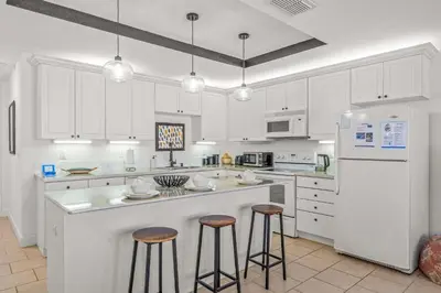 a kitchen with white cabinets and a large island with bar stools at Family Friendly Relax Villa in Kissimmee
