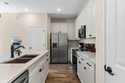 a kitchen with white cabinets and a stainless steel refrigerator at Flamingo Paradise in Orlando