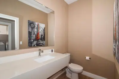 a bathroom with a sink and a toilet and a mirror at Villa at Magic Village Resort with Outdoor Oasis in Orlando