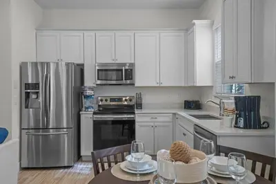 a kitchen with white cabinets and stainless steel appliances at Get Happy in Orlando