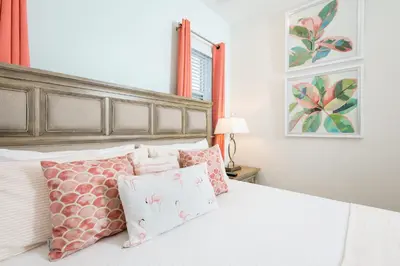 a bedroom with a bed with pink and white pillows at Trade Winds Life - Margaritaville in Orlando