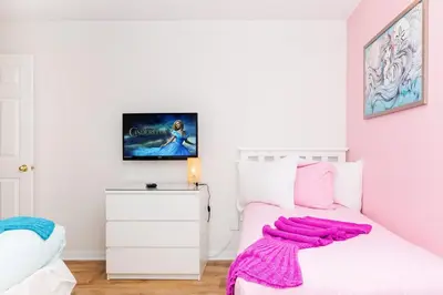 a bedroom with a white bed with a pink blanket on it at Jewel of Emerald Island with Heated Pool in Kissimmee