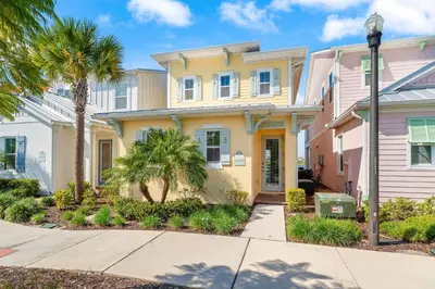 a yellow house with palm trees and a sidewalk at Lafitte's Landing Lakeview Cottage - Lakefront in Orlando