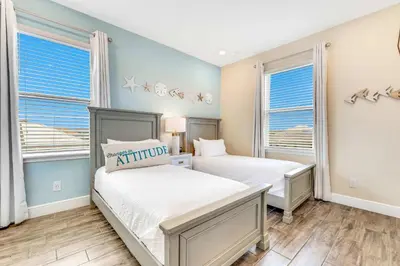 two beds in a bedroom with blue walls and windows at The Sea Shelter - Sunny 4 BDR in Margaritaville in Orlando