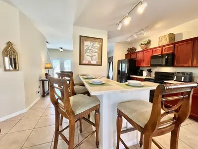 a kitchen with a island with chairs and a counter top at Marcellas Villa At Acadia Estates in Orlando