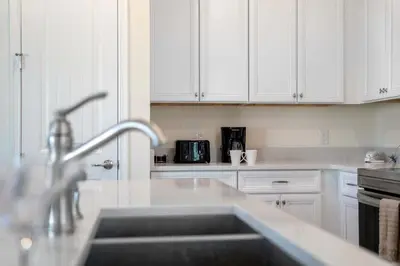 a kitchen with white cabinets and a sink at Mint to Be in Orlando