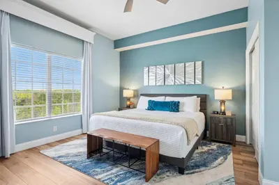 a bedroom with blue walls and a bed with a table at Minutes to Magic in Orlando