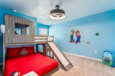 a childs bedroom with a bunk bed with a red bedspread at Once Upon a Stay in Kissimmee