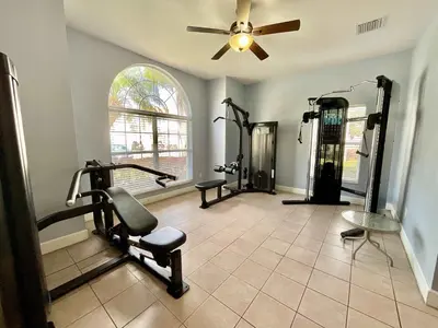 a gym with tread machines and a ceiling fan at Once Upon a Stay in Kissimmee