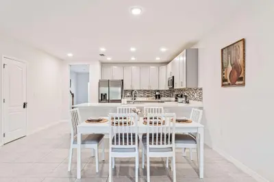 a white kitchen with a white table and chairs at Once Upon a Stay in Kissimmee