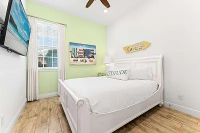 a bedroom with a white bed and a tv at Parrot Paradise Escape for 8 in Orlando