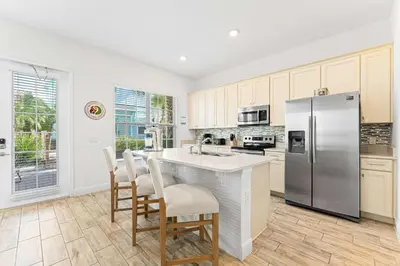a kitchen with a stainless steel refrigerator and white cabinets at Parrot Paradise Escape for 8 in Orlando