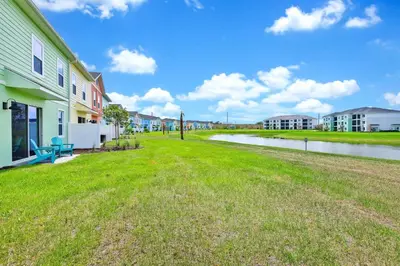 a grassy yard next to a river with buildings at Pistachio Palace - Sleeps 10 in Orlando